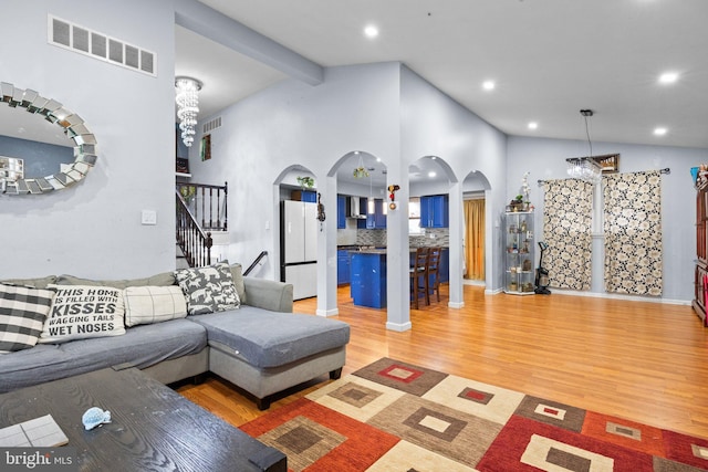 living room with beamed ceiling, high vaulted ceiling, and light hardwood / wood-style flooring