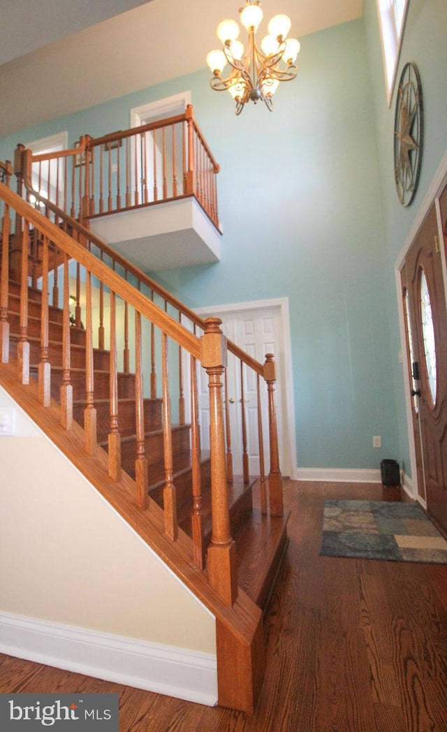 foyer entrance featuring hardwood / wood-style floors, a notable chandelier, and a towering ceiling