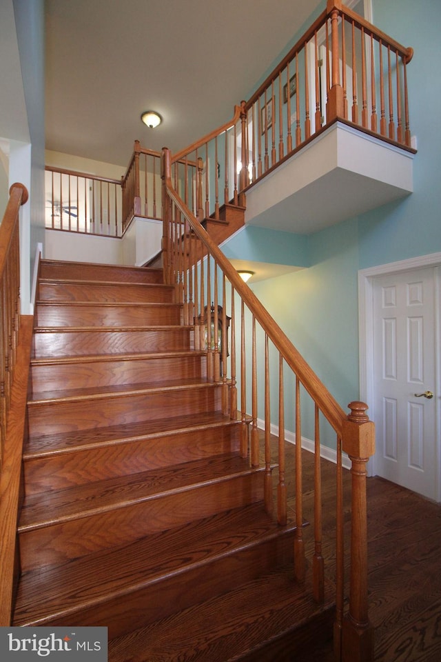 stairway with hardwood / wood-style floors and a high ceiling