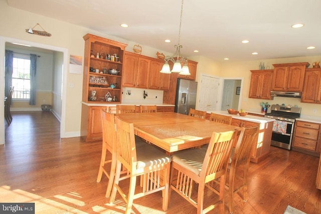 kitchen with pendant lighting, a center island, an inviting chandelier, dark hardwood / wood-style floors, and appliances with stainless steel finishes