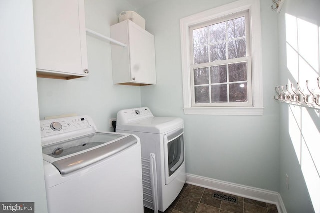 clothes washing area featuring cabinets, dark tile patterned flooring, and washer and clothes dryer