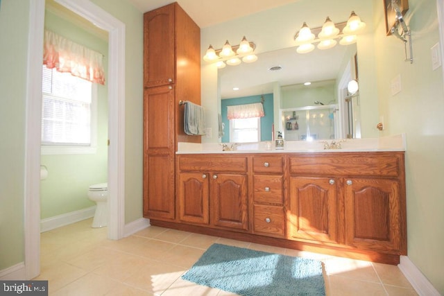 bathroom featuring tile patterned flooring, vanity, toilet, and a shower with shower door