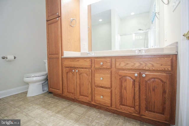 bathroom featuring a shower with door, vanity, and toilet