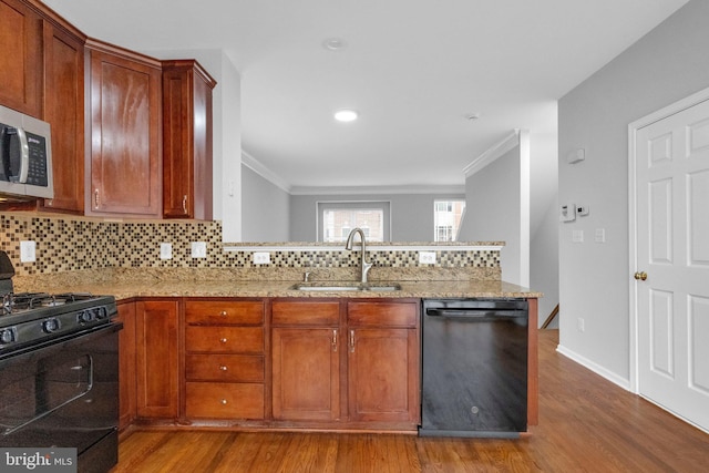 kitchen featuring decorative backsplash, light stone counters, sink, and black appliances