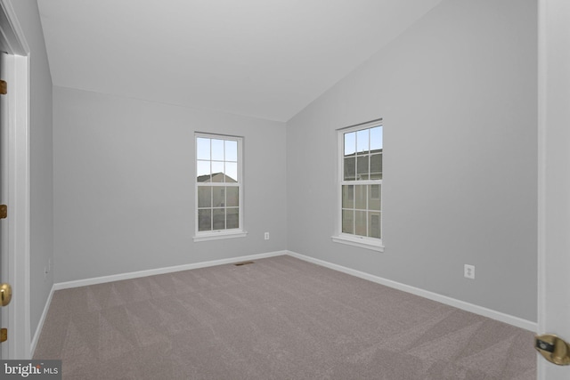 carpeted spare room featuring a wealth of natural light and vaulted ceiling