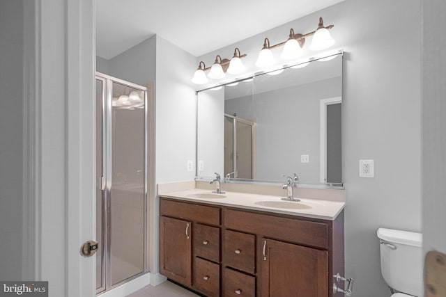 bathroom featuring tile patterned flooring, vanity, a shower with shower door, and toilet