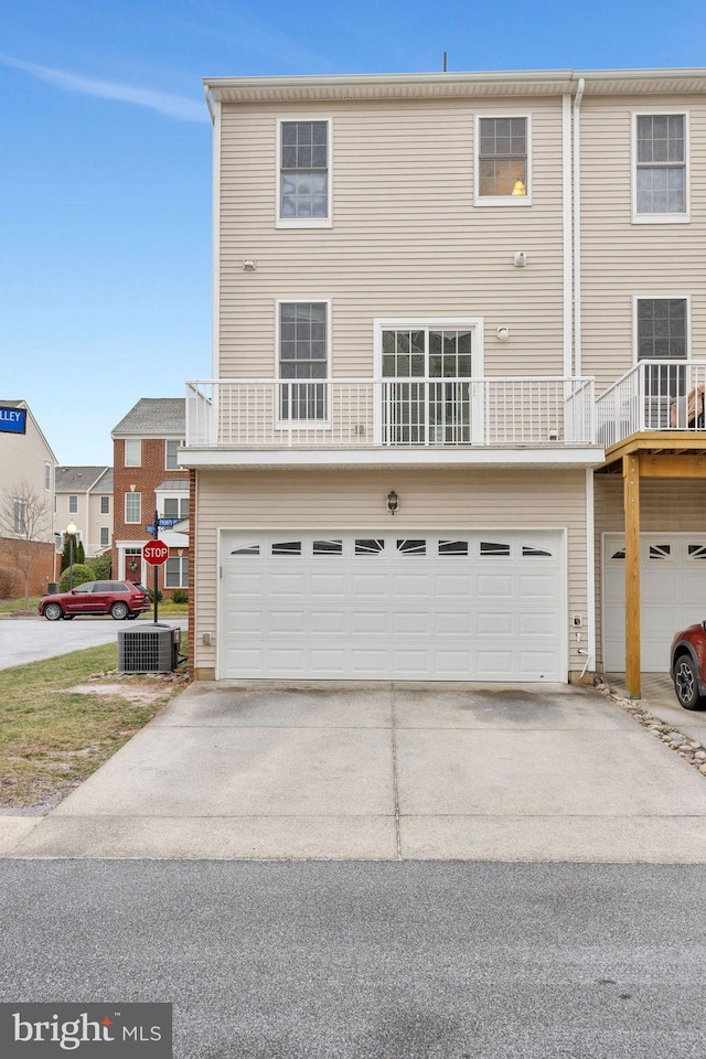 view of front of property featuring a garage, a balcony, and central AC