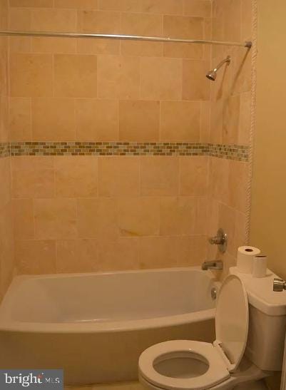 bathroom with tiled shower / bath combo and toilet