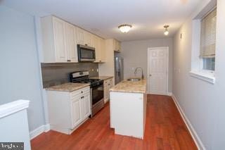 kitchen featuring appliances with stainless steel finishes, tasteful backsplash, dark wood-type flooring, sink, and white cabinets