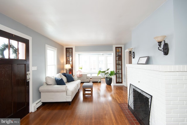 living room featuring a fireplace, dark hardwood / wood-style flooring, baseboard heating, and ceiling fan