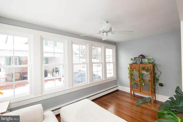 living area with baseboard heating, dark wood-type flooring, and ceiling fan