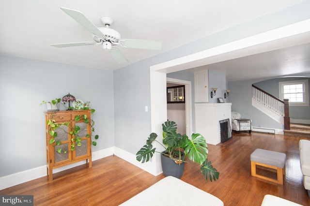 living room with hardwood / wood-style flooring, ceiling fan, a fireplace, and a baseboard radiator