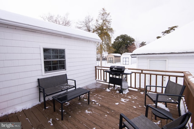 snow covered deck featuring a grill and a storage unit