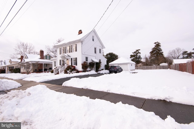 view of snowy exterior featuring an outdoor structure and a garage