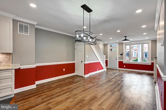 interior space featuring ornamental molding, ceiling fan with notable chandelier, and dark wood-type flooring