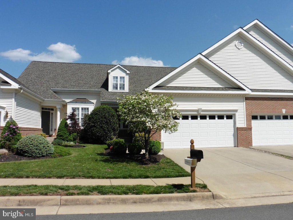 view of front facade with driveway, brick siding, an attached garage, and a front yard