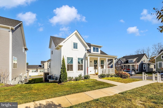 view of front facade featuring covered porch, a front yard, and central AC