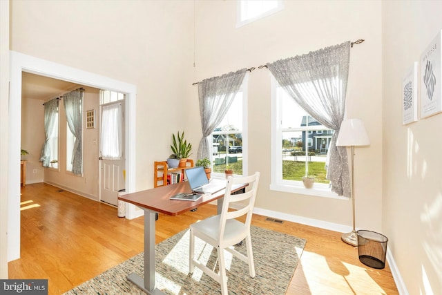 office featuring light hardwood / wood-style floors and a high ceiling