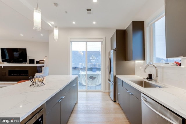 kitchen with decorative light fixtures, gray cabinets, sink, and appliances with stainless steel finishes