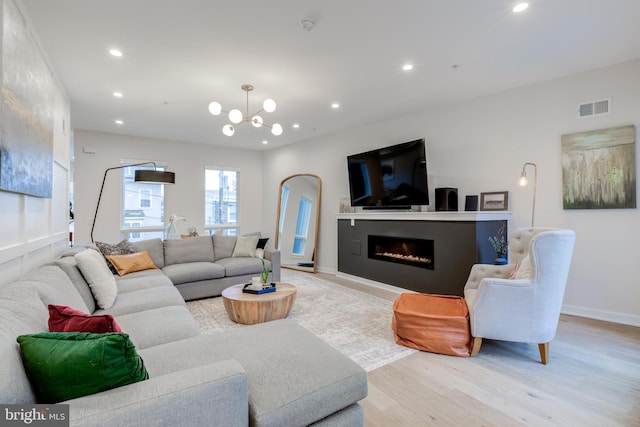 living room with light wood-type flooring and an inviting chandelier