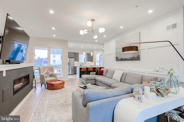 living room featuring light wood-type flooring and an inviting chandelier