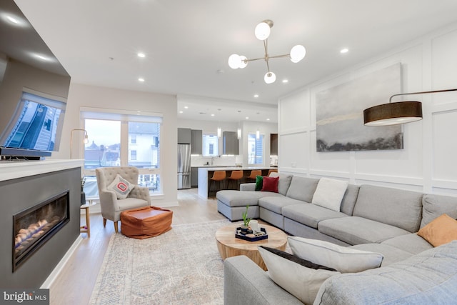 living room with a notable chandelier and light wood-type flooring