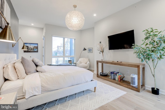 bedroom featuring an inviting chandelier and light hardwood / wood-style flooring