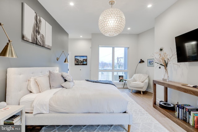 bedroom with a chandelier and light wood-type flooring