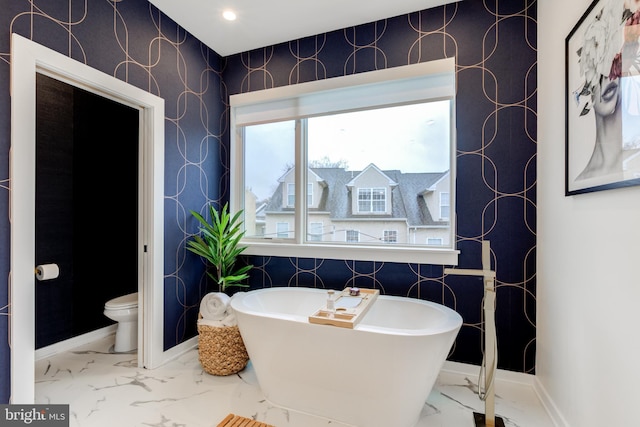 bathroom with toilet and a tub to relax in