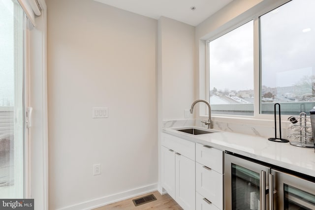 interior space with white cabinetry, light stone counters, sink, and a healthy amount of sunlight