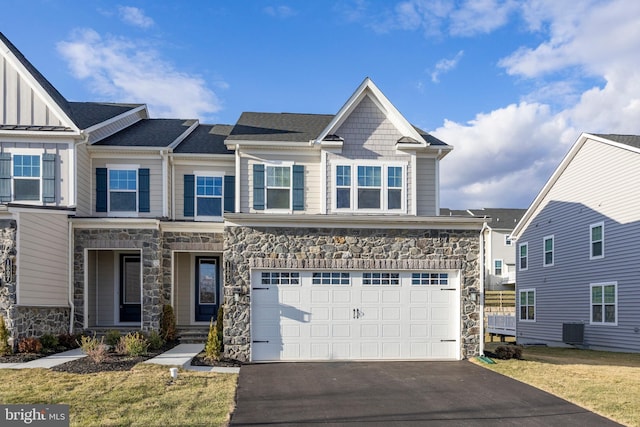 view of front facade featuring aphalt driveway, an attached garage, central AC, stone siding, and board and batten siding