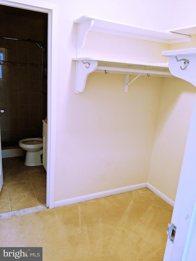 interior space featuring tile patterned floors, vanity, toilet, and tiled shower