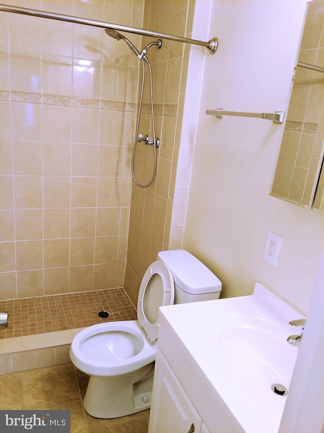 bathroom with tiled shower, tile patterned floors, vanity, and toilet