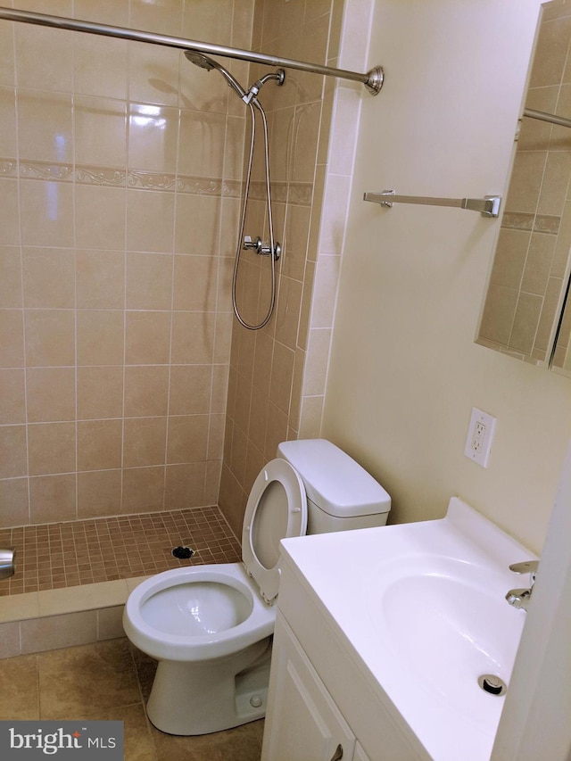 bathroom with tile patterned floors, vanity, toilet, and tiled shower