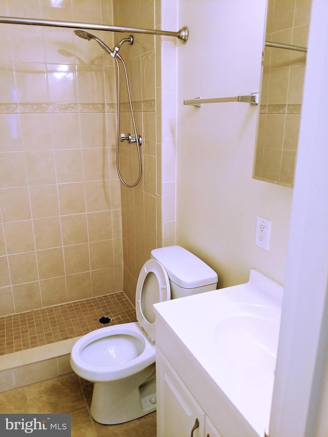 bathroom featuring tile patterned flooring, a tile shower, vanity, and toilet