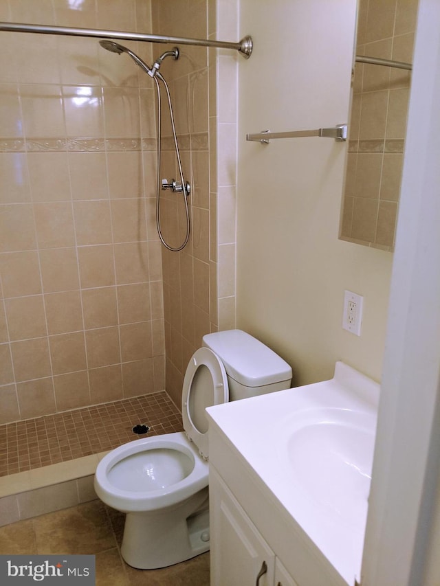 bathroom featuring tile patterned floors, vanity, toilet, and a tile shower