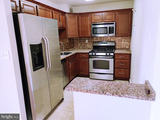 kitchen with decorative backsplash, appliances with stainless steel finishes, light stone countertops, sink, and light tile patterned flooring