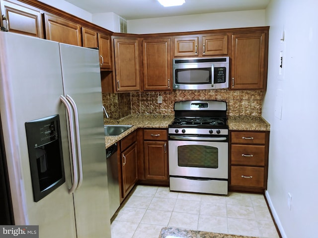 kitchen with decorative backsplash, appliances with stainless steel finishes, light stone counters, and sink