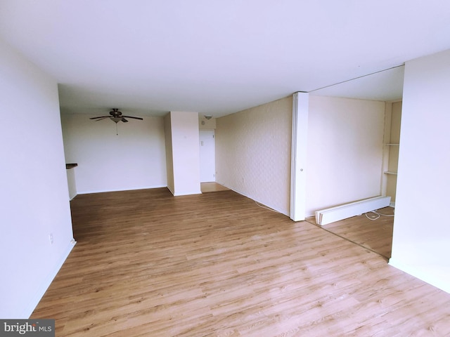 empty room featuring baseboard heating, ceiling fan, and light hardwood / wood-style floors