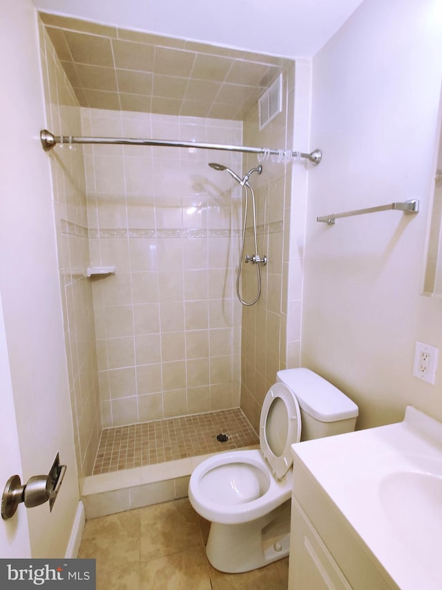 bathroom featuring a tile shower, tile patterned floors, vanity, and toilet