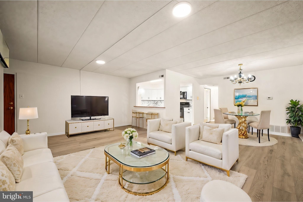 living room with light hardwood / wood-style floors and a notable chandelier