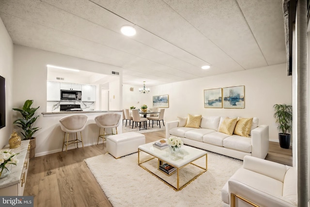 living room with light hardwood / wood-style flooring and a notable chandelier