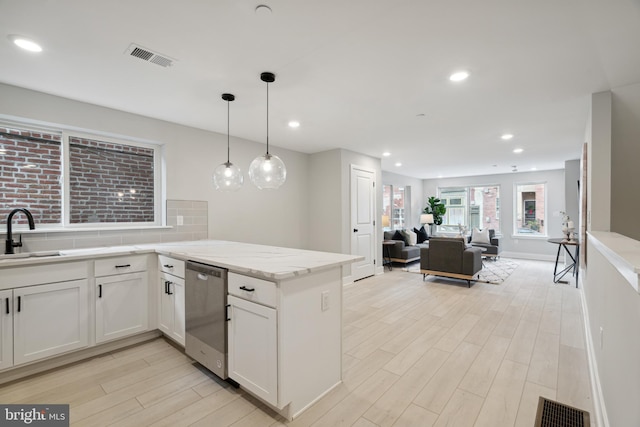 kitchen with light stone countertops, white cabinetry, dishwasher, sink, and pendant lighting