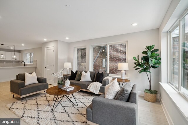 living room with a healthy amount of sunlight, sink, and light hardwood / wood-style floors