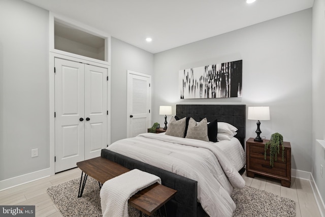 bedroom featuring multiple closets and light hardwood / wood-style flooring