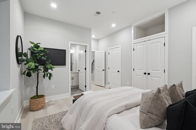 bedroom with ensuite bathroom and light hardwood / wood-style floors