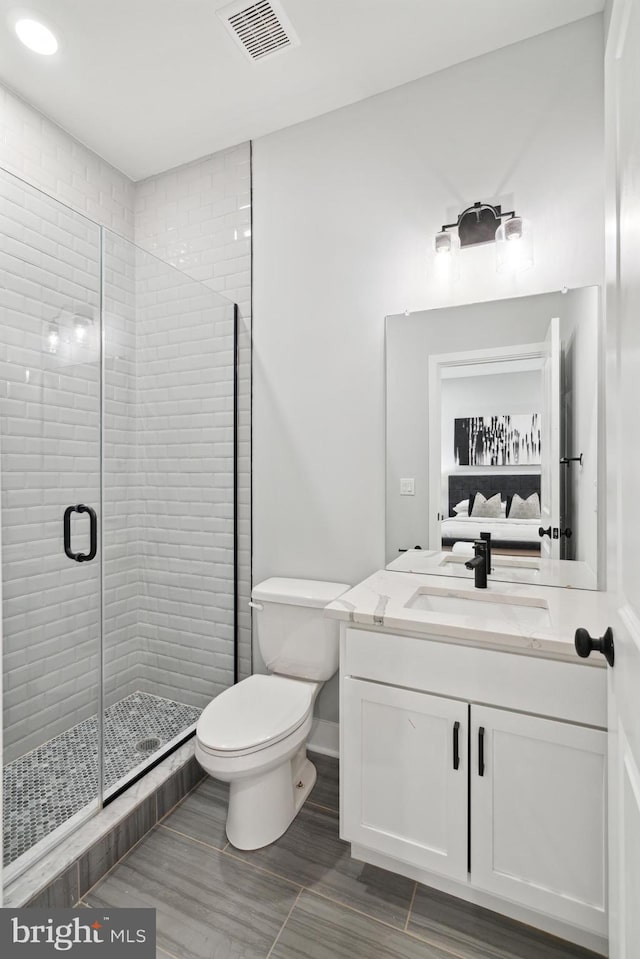 bathroom with vanity, toilet, and a shower with door