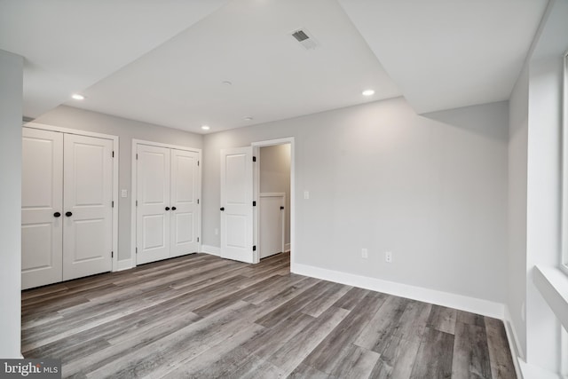 unfurnished bedroom with two closets and light hardwood / wood-style flooring