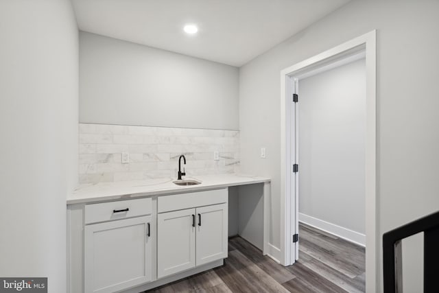 bar with sink, dark hardwood / wood-style floors, decorative backsplash, light stone countertops, and white cabinetry