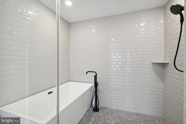 bathroom with tile walls and independent shower and bath